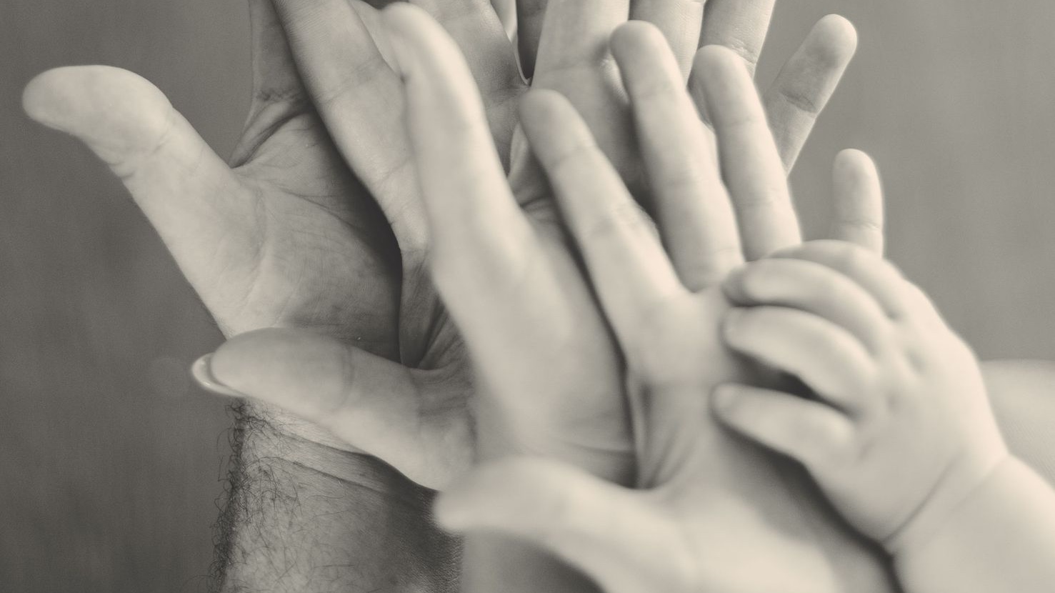 grayscale photo of family's hands