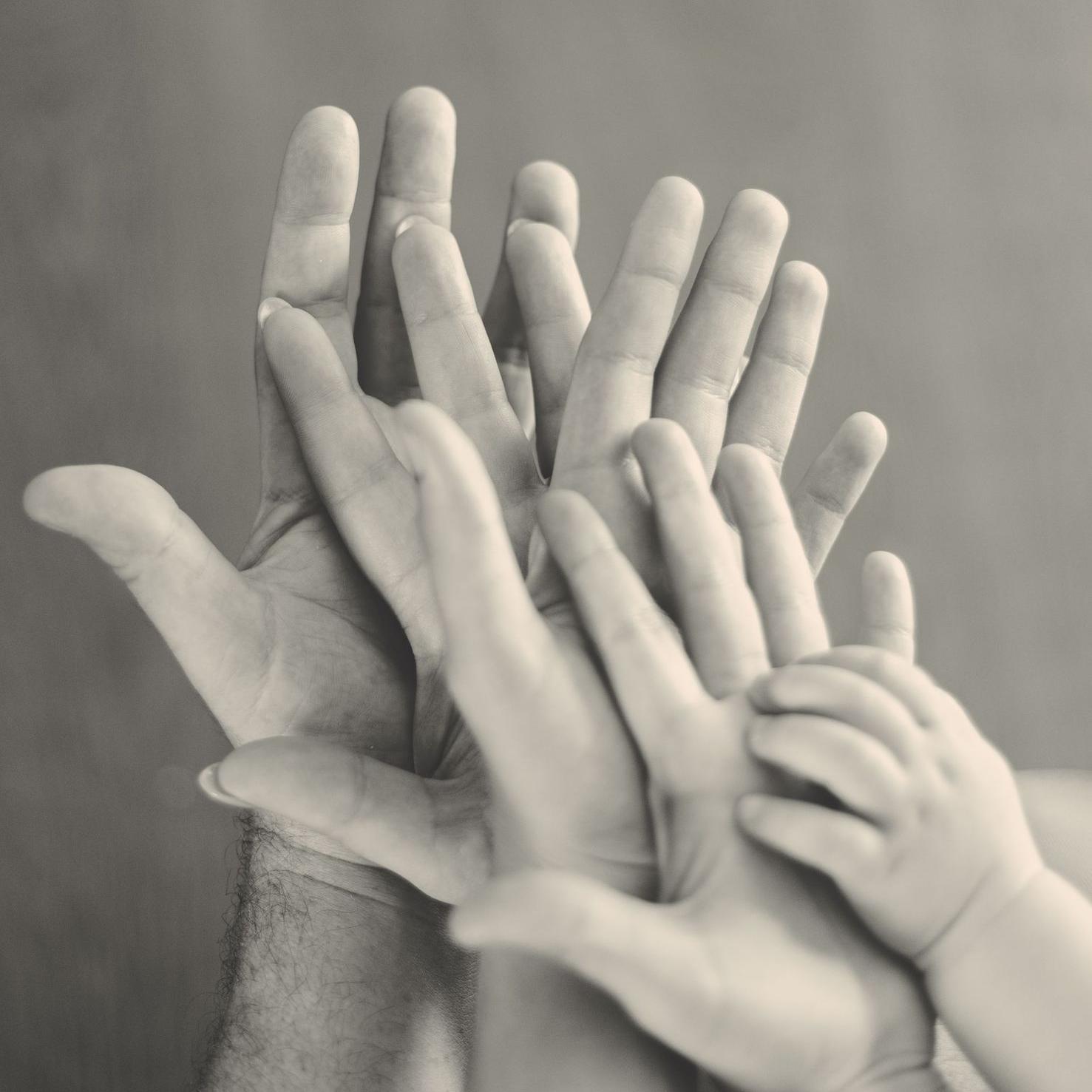 grayscale photo of family's hands